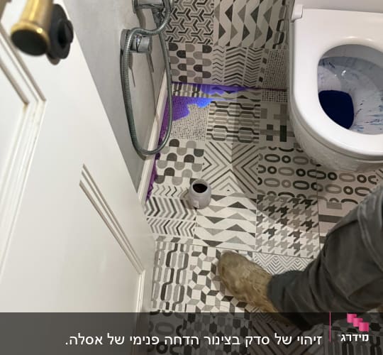 רגל של אינסטלטור ליד אסלה עם נזילה